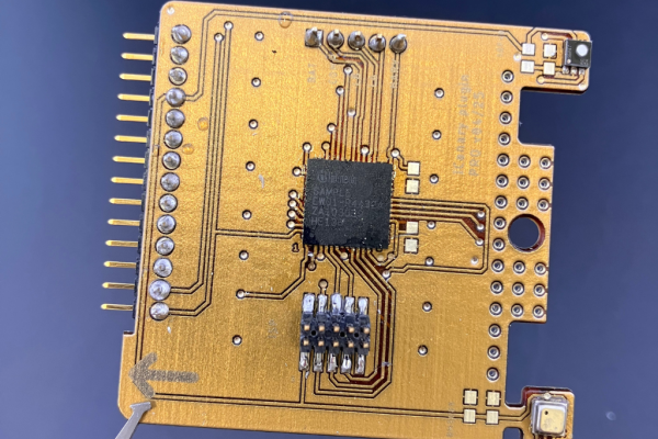 Nahaufnahme einer goldenen mehrlagigen Leiterplatte (PCB) mit Mikrochip und Kontaktpins – Elektronik Prototyp und Platinenlayout im Detail.