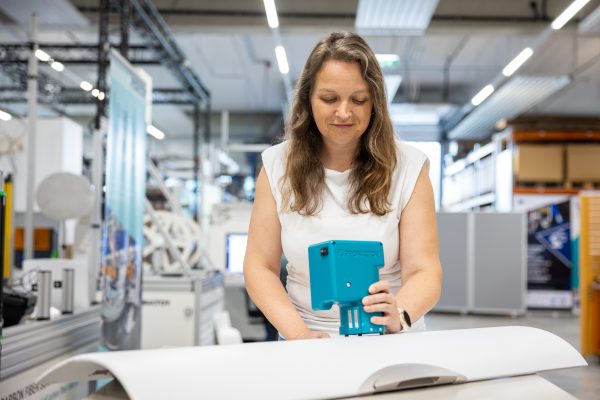 Mitarbeiterin verwendet Sensor zur Qualitätsprüfung auf Gepäckfach