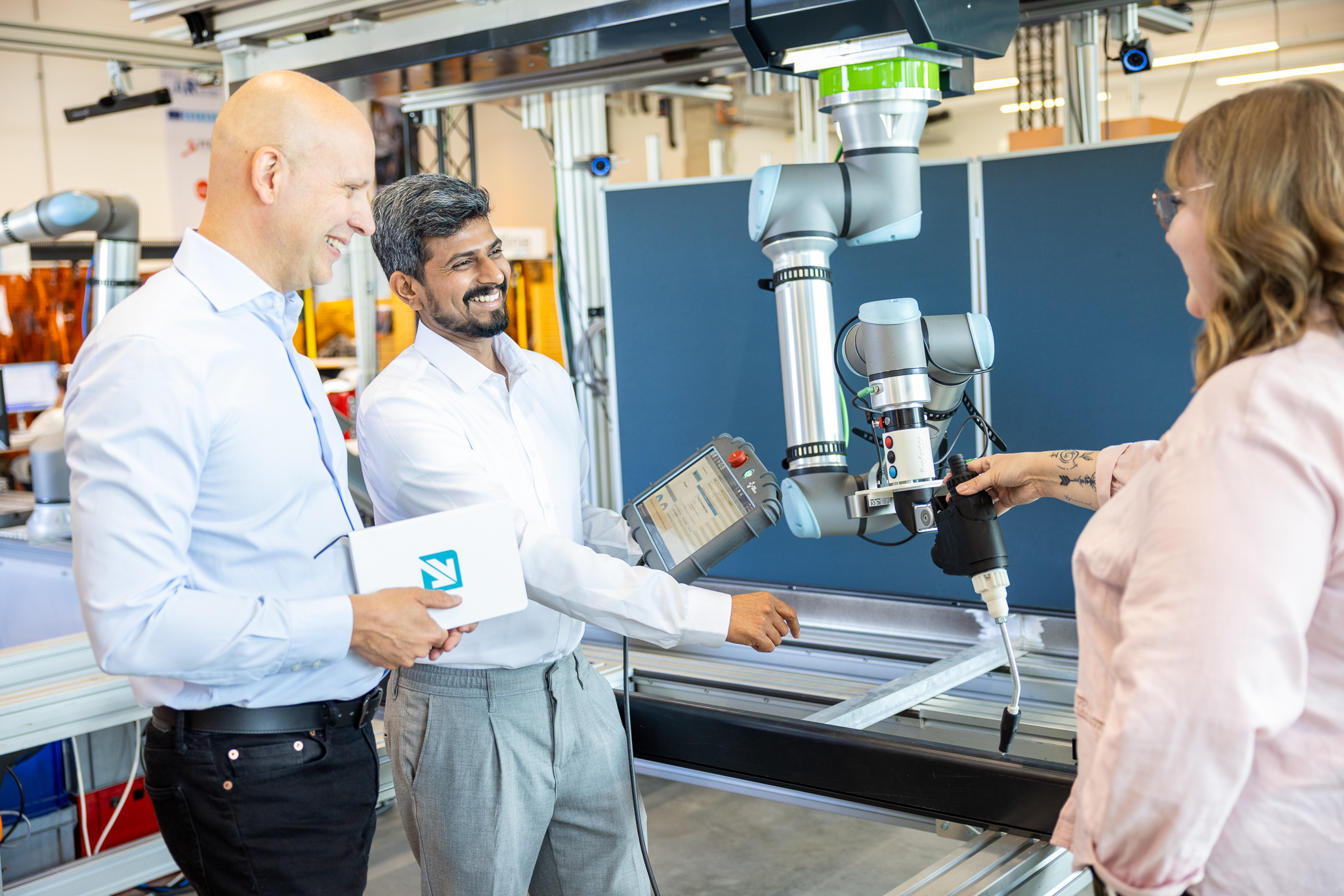 Mitarbeiter:innen haben eine Besprechung im Labor bei einem Roboter.