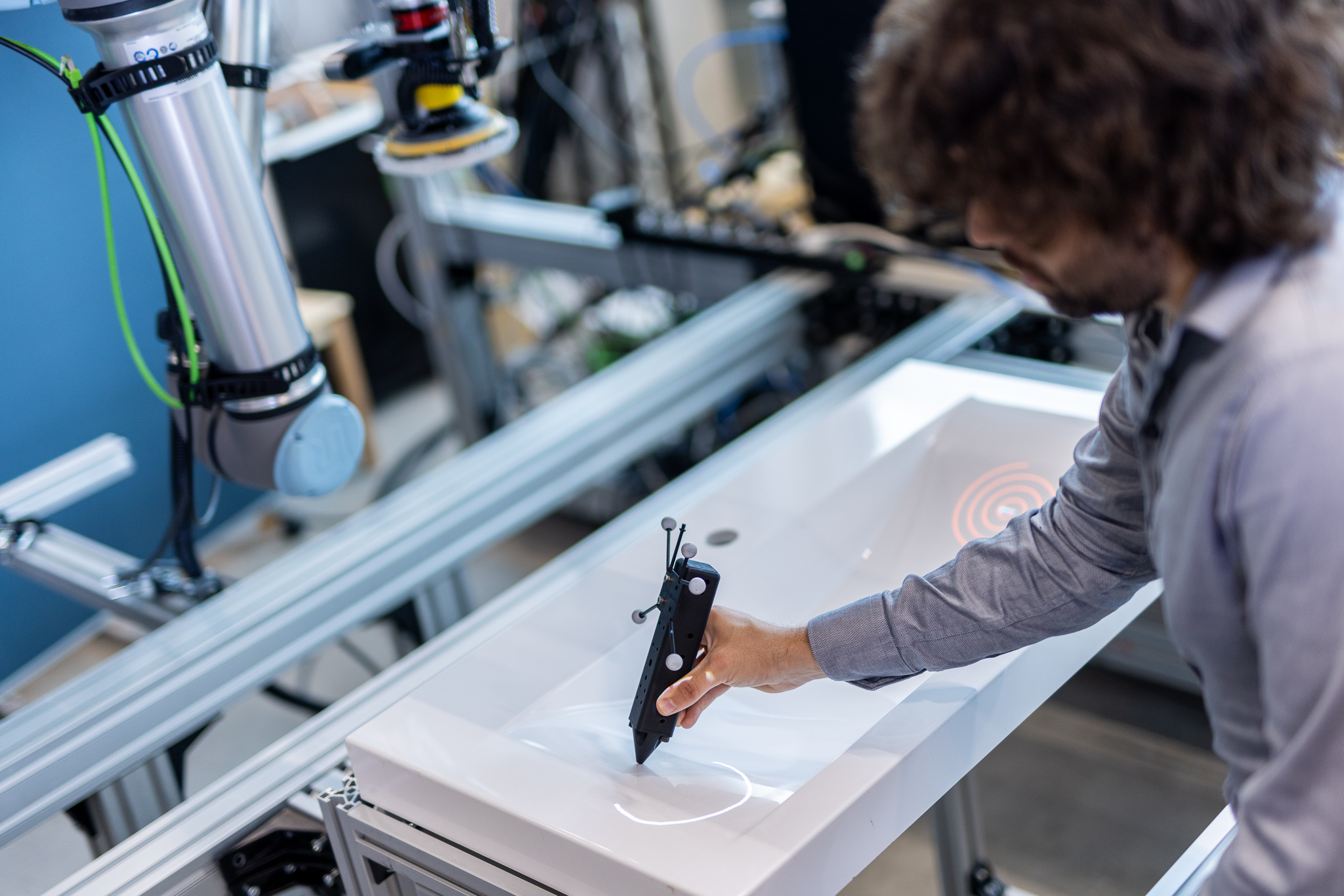 Mitarbeiter steuert Roboter mittels Stift am Waschbecken