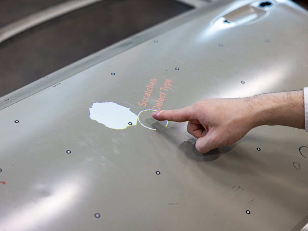Automatisierung: Assistenzsystem erkennt Handbewegung und markiert einen Fehler digital auf einem Bauteil in der Produktion