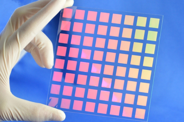 Hand mit Laborhandschuh hält transparente Glasplatte mit nanostrukturiertem Farbfilter-Array für Augmented-Reality- und optische Anwendungen, hergestellt mittels Nanoimprint-Lithographie.