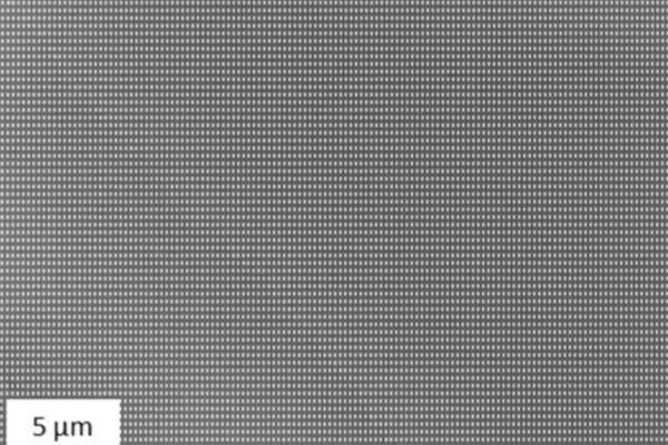 Mikroskopische Aufnahme eines nanostrukturierten Arrays mit regelmäßigen Mikro- und Nanoporen (Maßstab 5 µm), hergestellt mittels Nanoimprint-Lithographie für Anwendungen in Nanofluidik und Life Sciences.