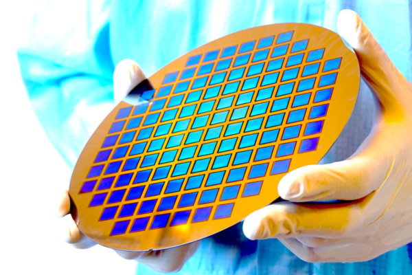 Halbleiter-Wafer mit Mikrostruktur-Array aus der Nanoimprint-Lithographie, gehalten von einer behandschuhten Hand im Reinraumlabor.